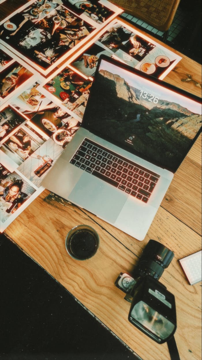 Chi Siamo Flat lay of a creative workspace with a laptop, camera, and printed photographs.